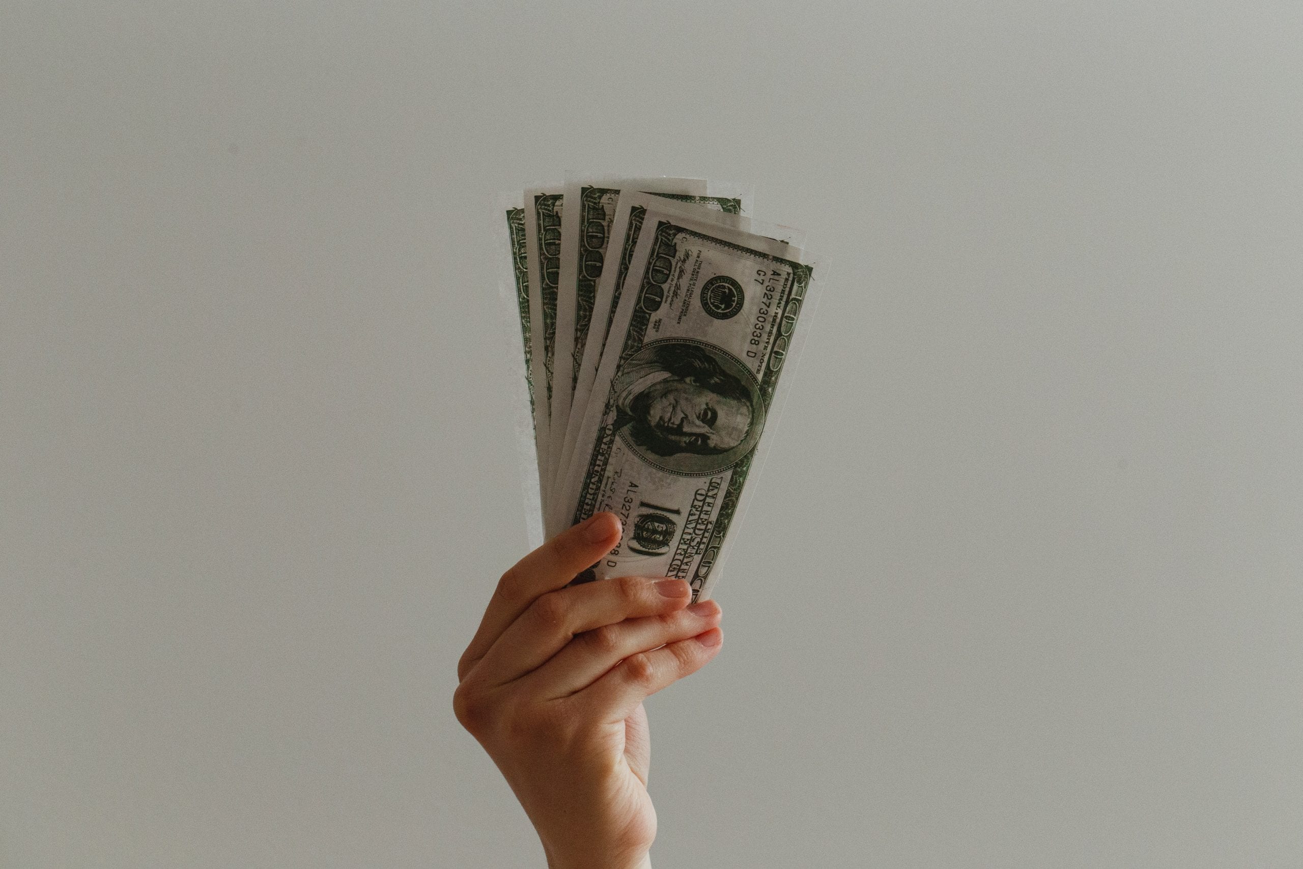 A person holding five $100 notes.