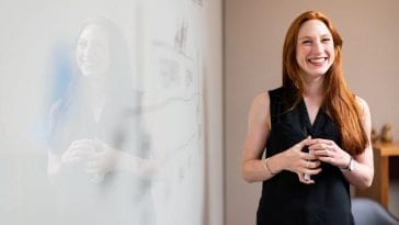 Teacher standing in front of a whiteboard and smiling